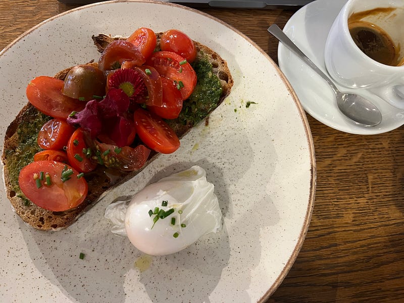 Tomatoes on sourdough toast, with a poached egg on the side.